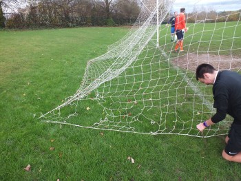 The referee examines the net, which clearly has several hole. 